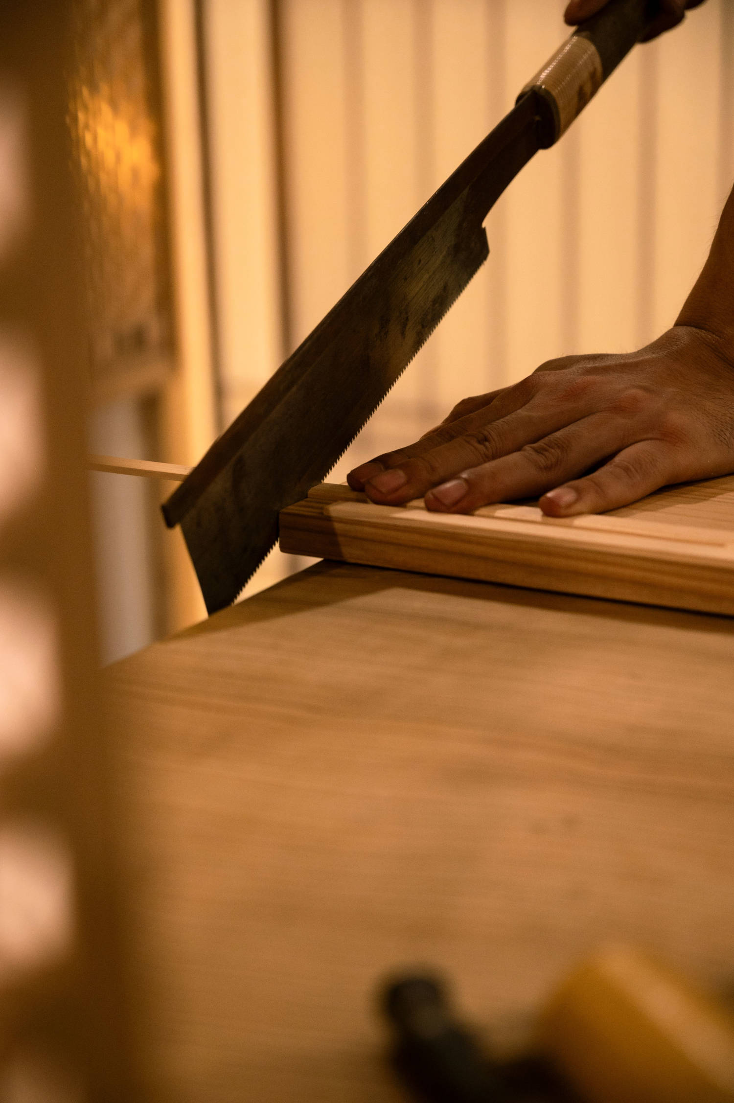 A craftsman hand-cutting a wood joint with a traditional Japanese pull saw